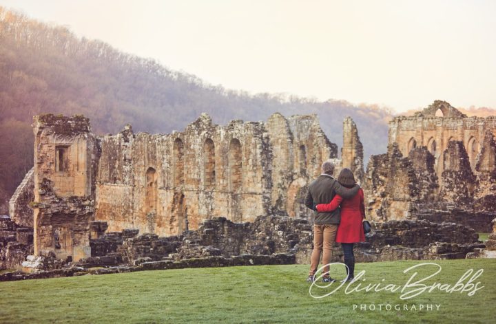couple standing together looking over Rievaulx Abbey in North York Moors National Park