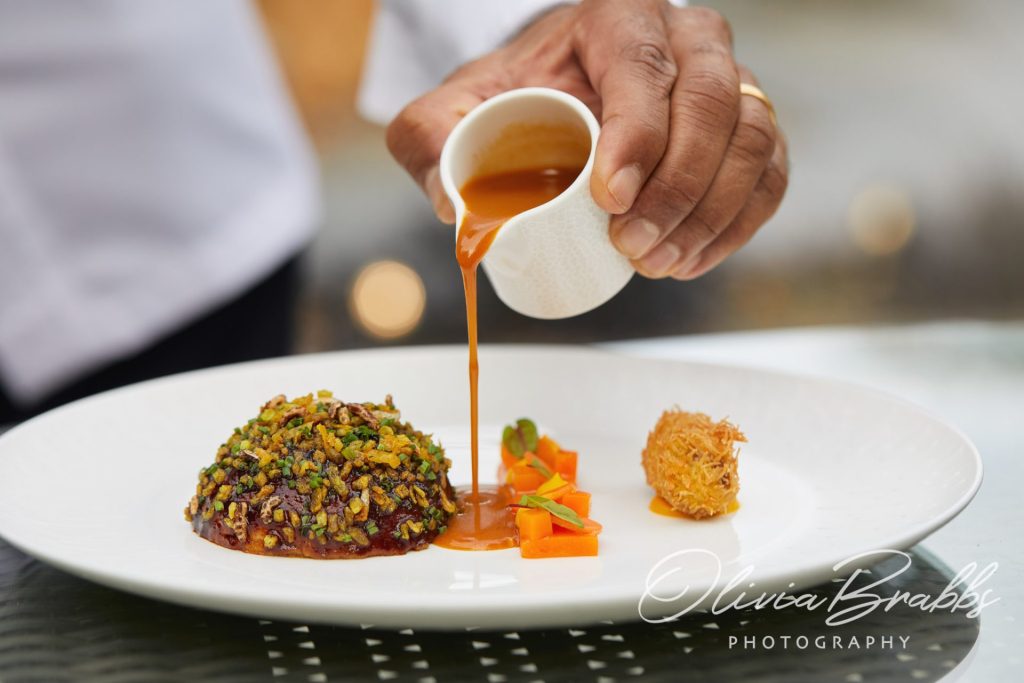 hand of michelin star chef Hrishikesh Desai plating lamb dish