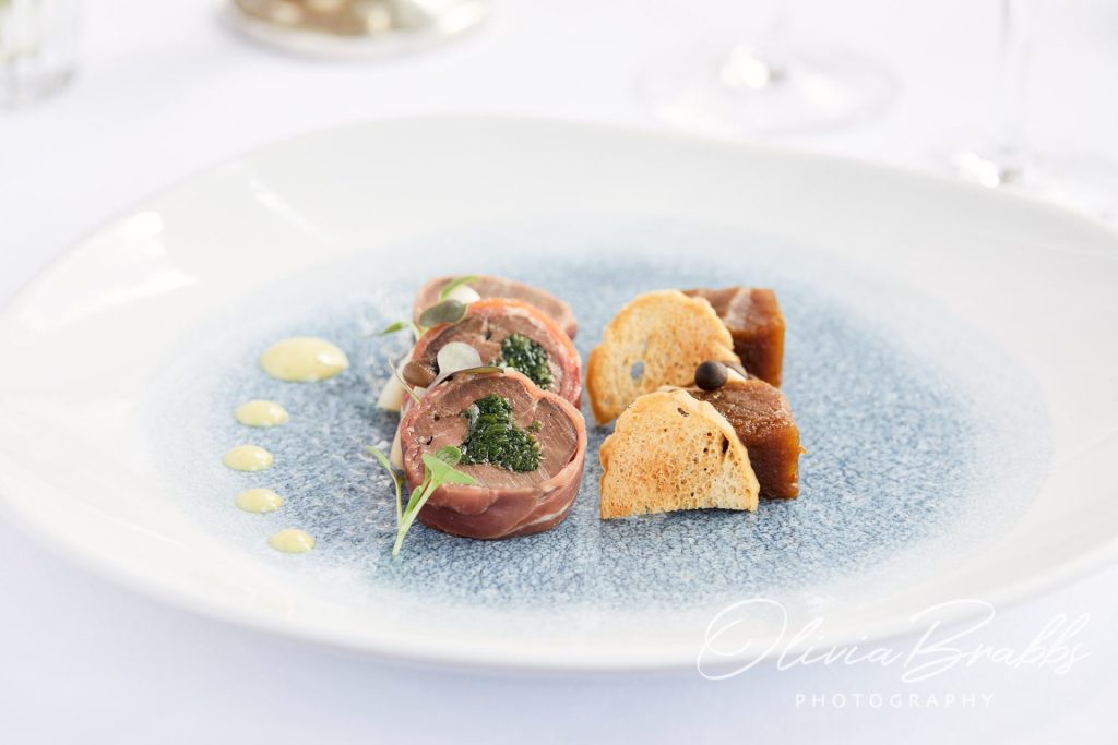 fine dining food photography for hotel showing main course with out of focus glasses behind
